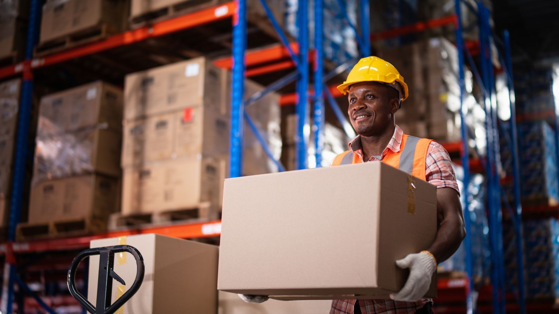 Man smiling and carrying a box in a warehouse