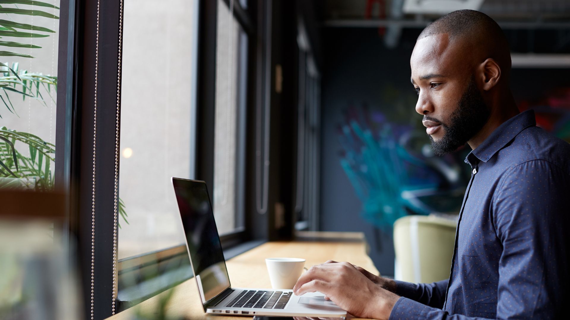 A man working on a laptop by a window