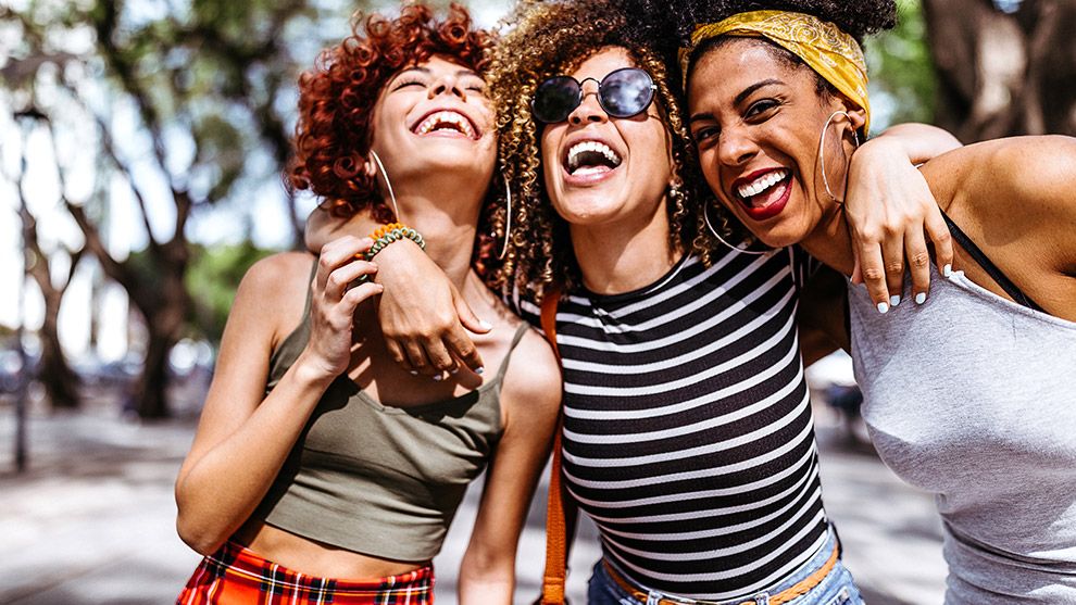 Three women smiling with their arms round each other 