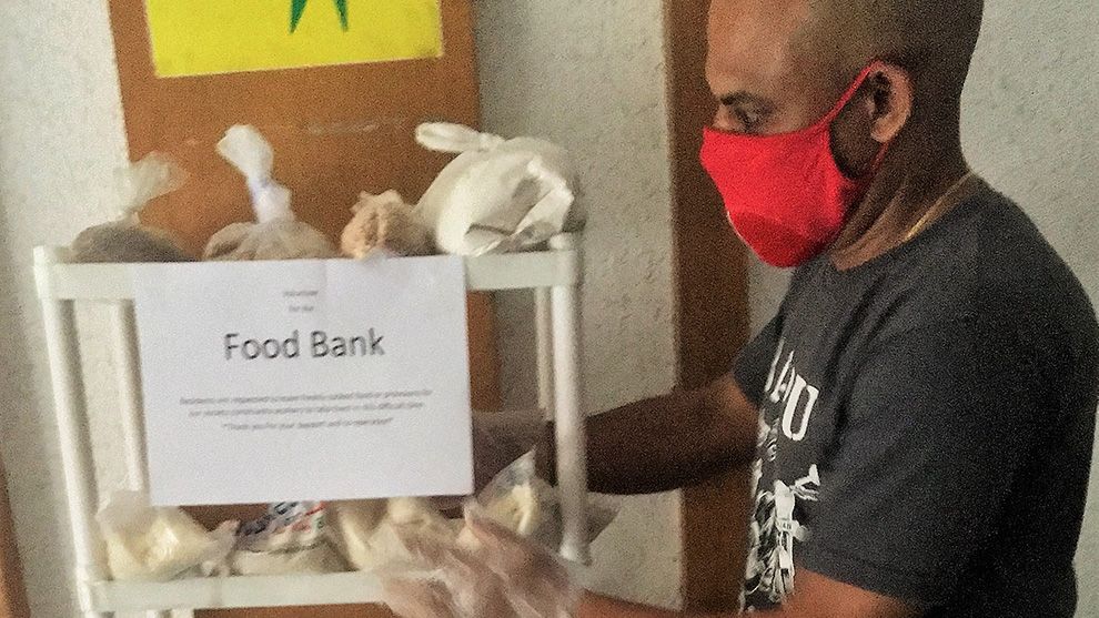 Man in red mask next to Food Bank shelf