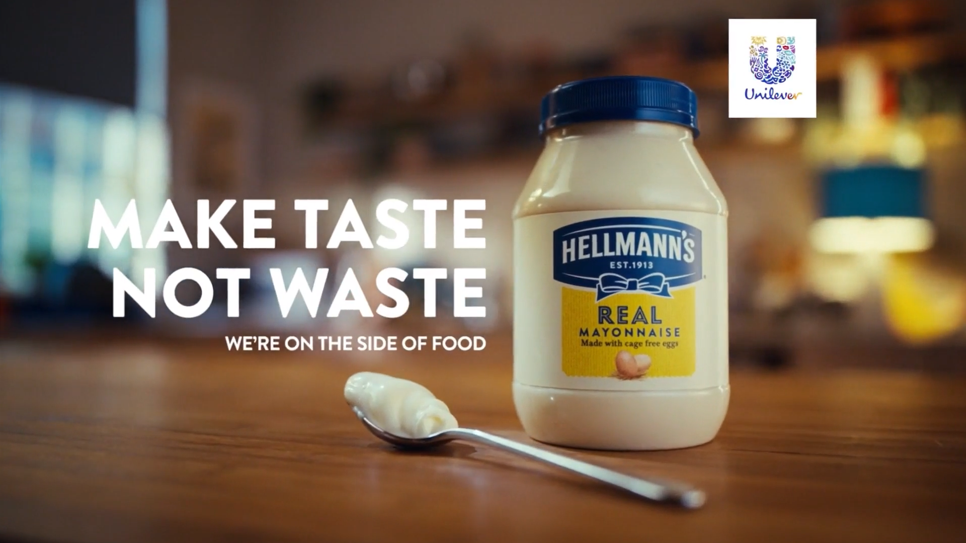 A bottle of Hellmann’s Mayonnaise on a table. Beside it is a spoon full of mayonnaise and text which reads, ‘Make taste not waste’ and ‘We’re on the side of food'.