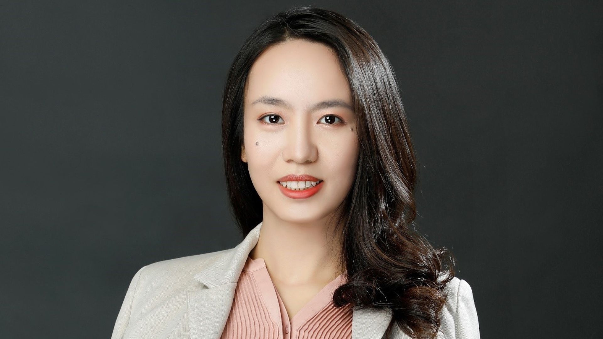 Erica Liang, a scientist at the Pond’s Skin Institute. Erica has long dark hair, a pink blouse and a white lab coat 