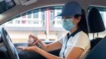 Female driver wearing face mask and cleaning hands with sanitiser. Unilever provides hygiene kits to Uber drivers and couriers.