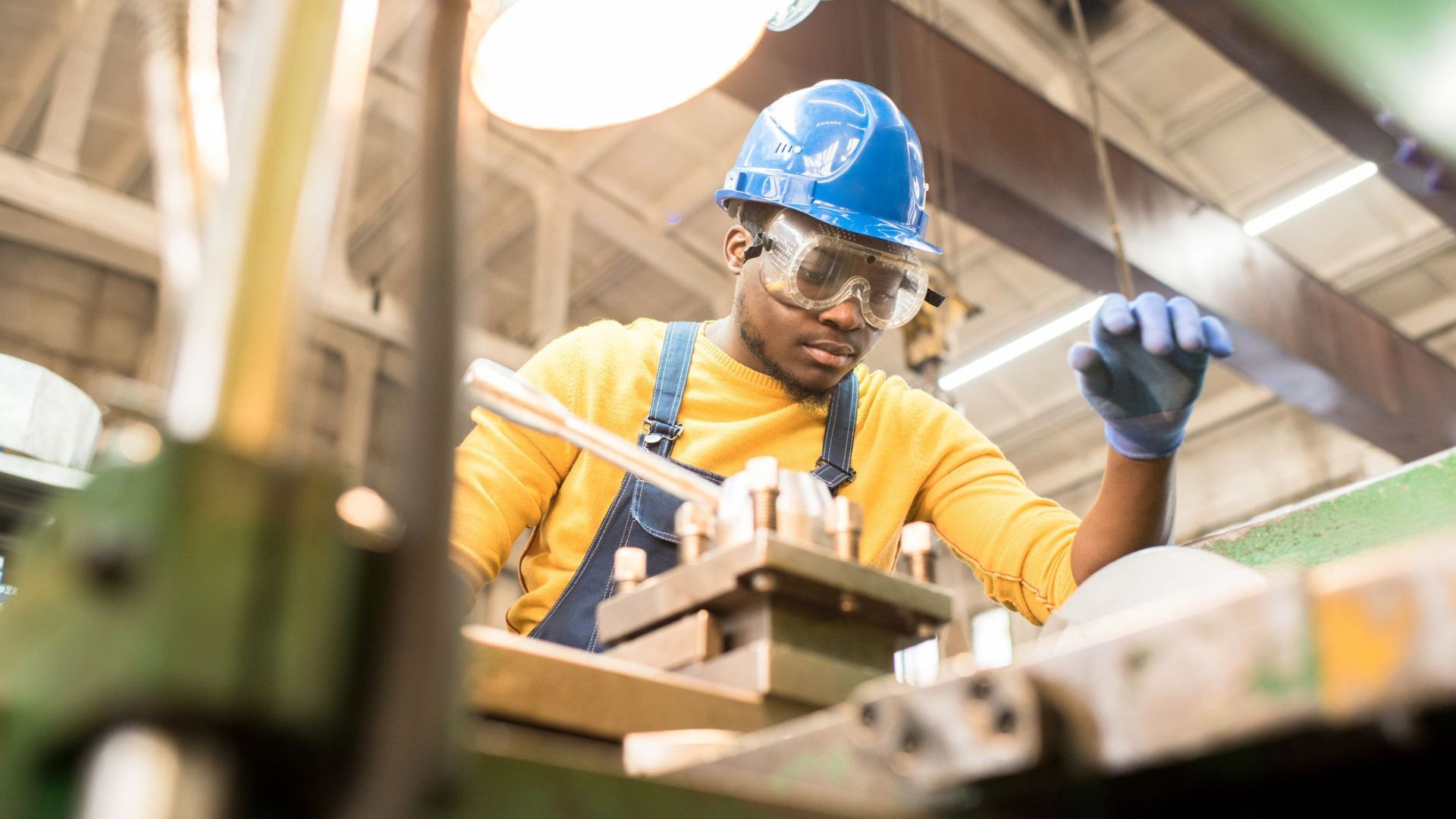 Man wearing hard hat and safety glasses working at a machine in a workshop