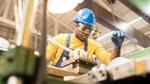 Man wearing hard hat and safety glasses working at a machine in a workshop