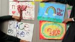 children’s hands pin pictures with place2be written on them onto a wall