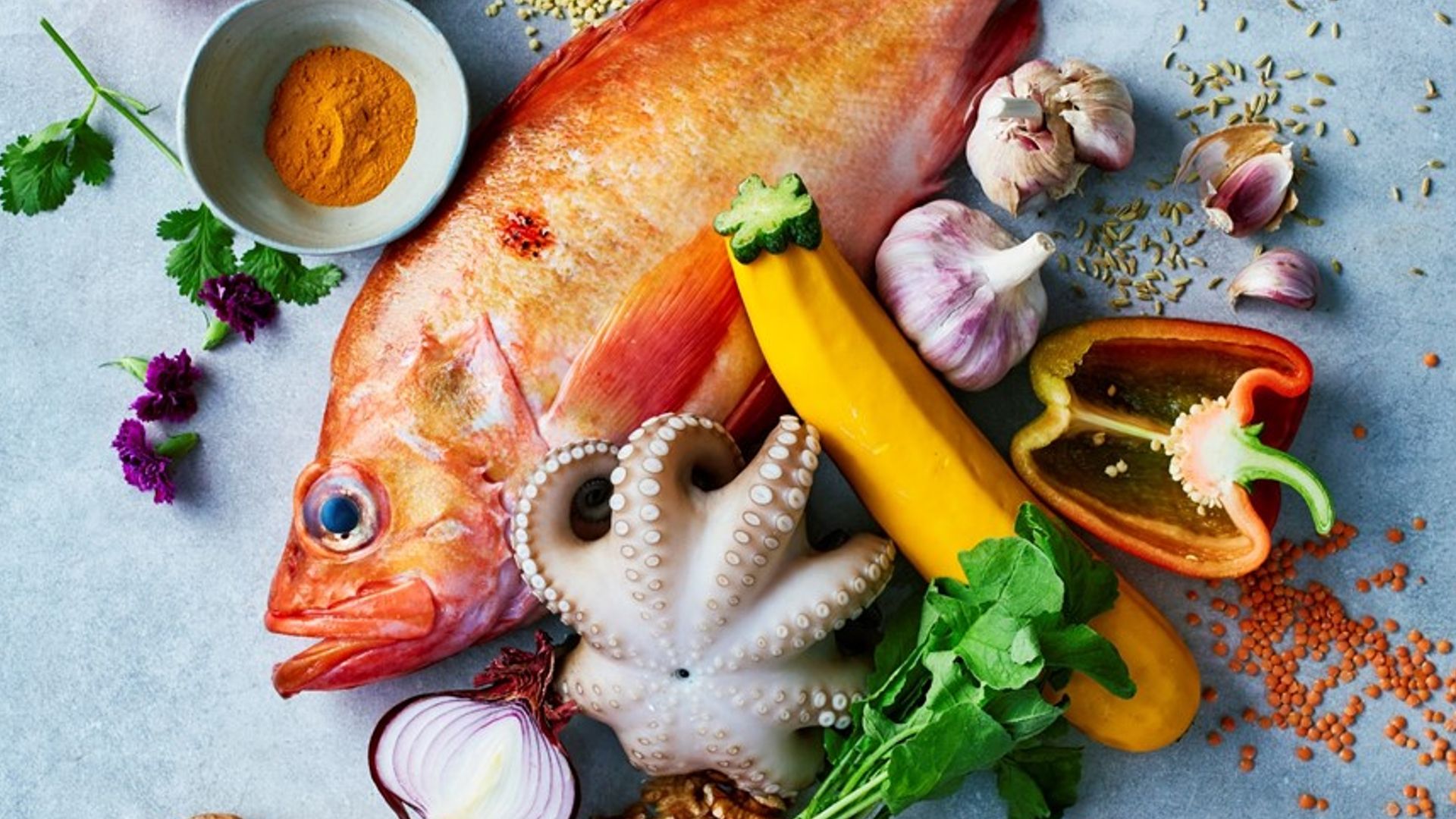A selection of foods including shallots, lemons and fish 