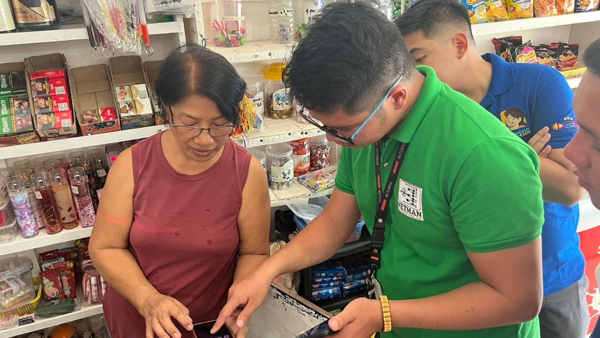 A man helps a woman work with an app in a store.