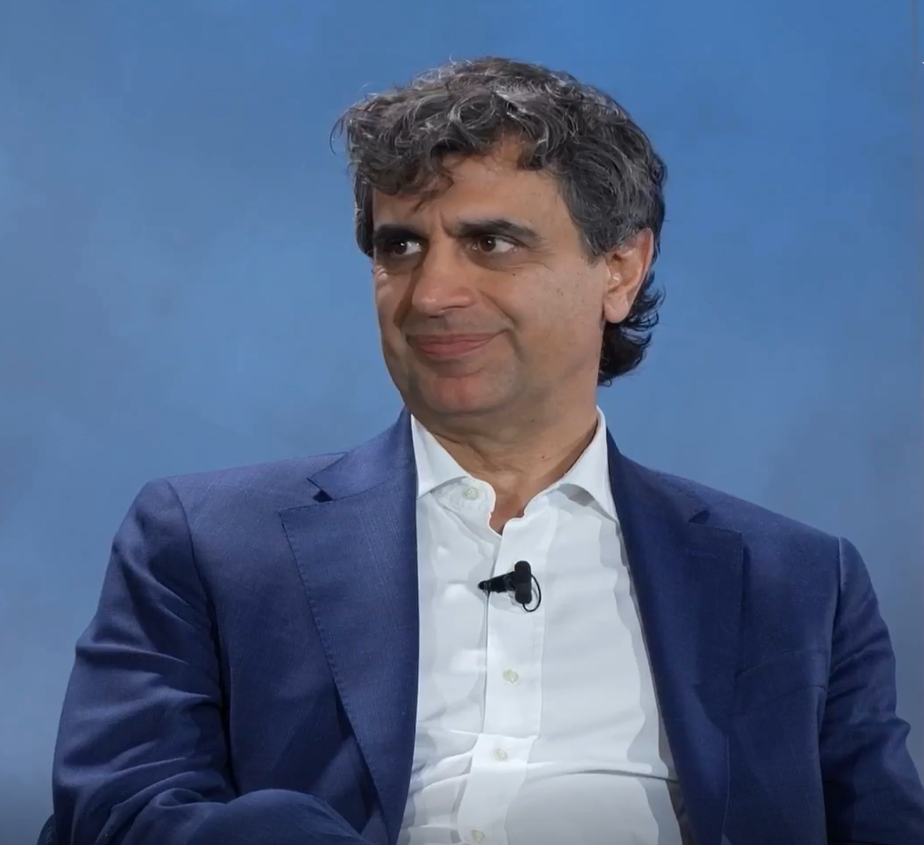 Fernando Fernandez wears a blue blazer and white shirt with a lapel microphone speaking at a WSJ Leadership Institute event
