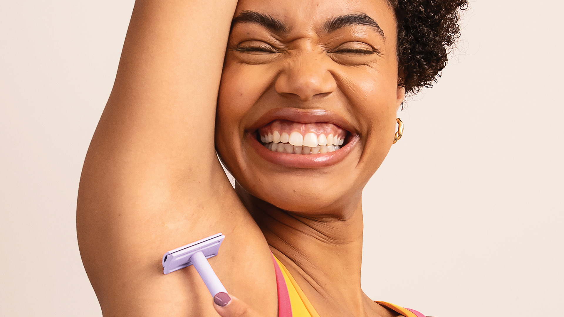 A smiling woman shaving her armpit 
