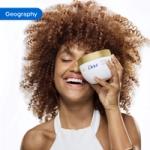 Person holding a Dove body care product in a bathroom setting with white tiles in the background. The image is tagged ‘Geography’.