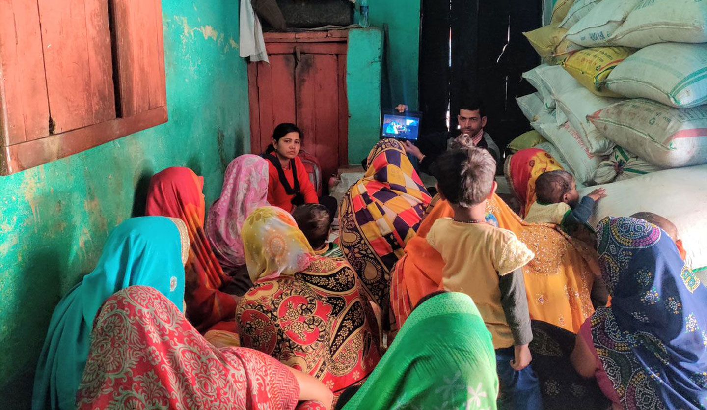 Women sit together watching an iPad as part of a local workshop