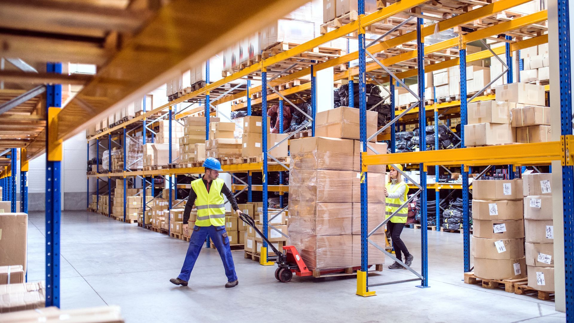 Warehouse of a packaging company featuring two employees pulling a palate