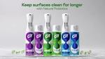 Six Cif Infinite Clean spray bottles with purple, green, and blue labels arranged in a row. Text above reads 'Keep surfaces clean for longer with Natural Probiotics.' Small green and white spheres are scattered at the bottom of the image.