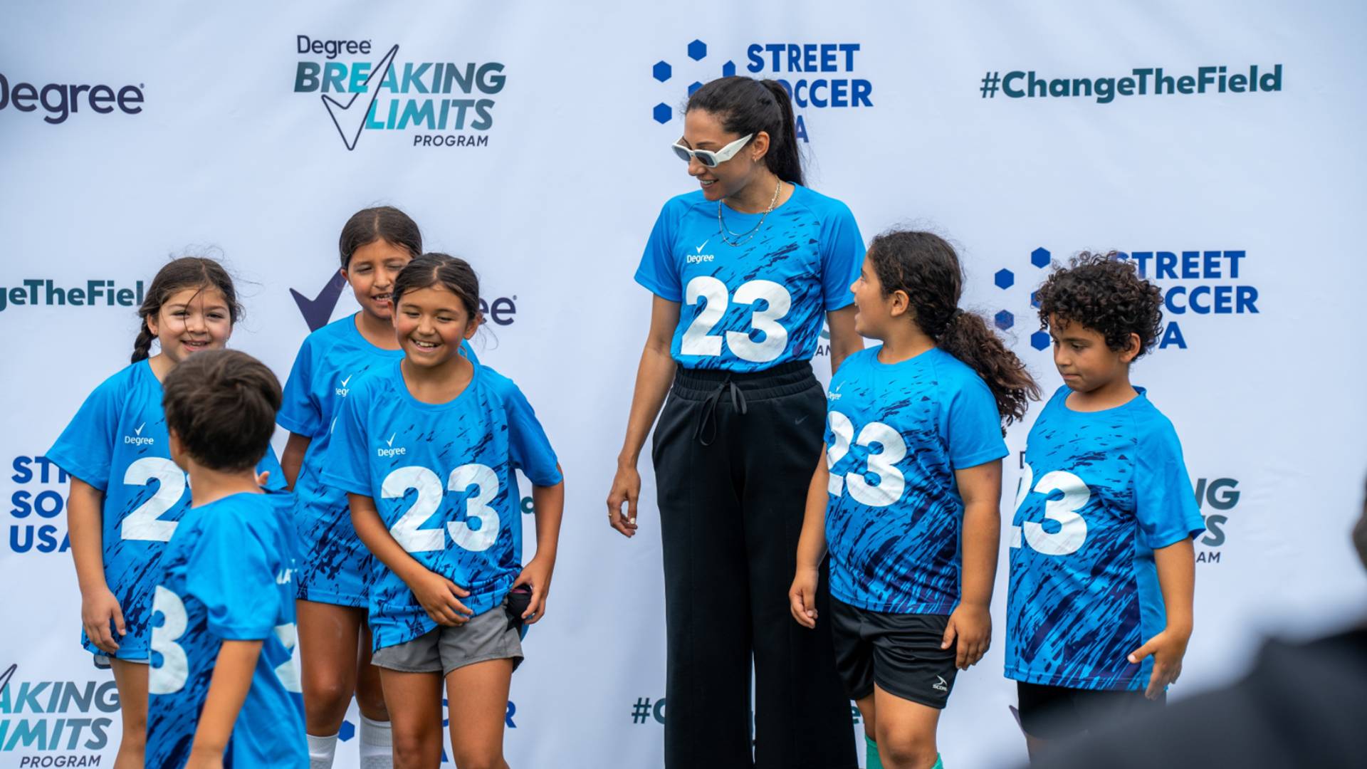 Footballer Christen Press smiling with a group of girls at a Rexona/Degree Change the Field event. 
