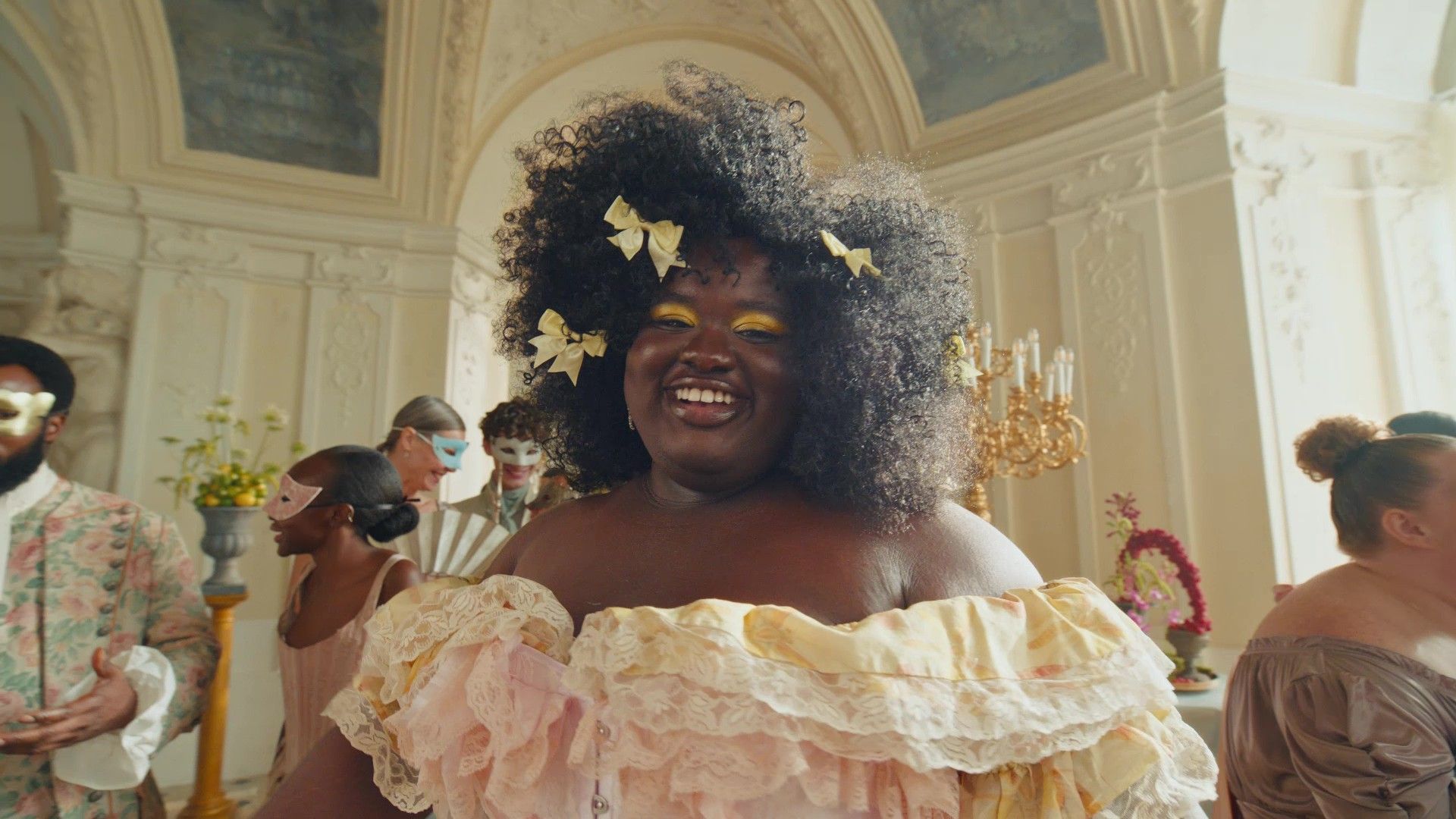 A woman wearing a ruffled pastel dress in an ornate ballroom. Dove has collaborated with Netflix series Bridgerton.