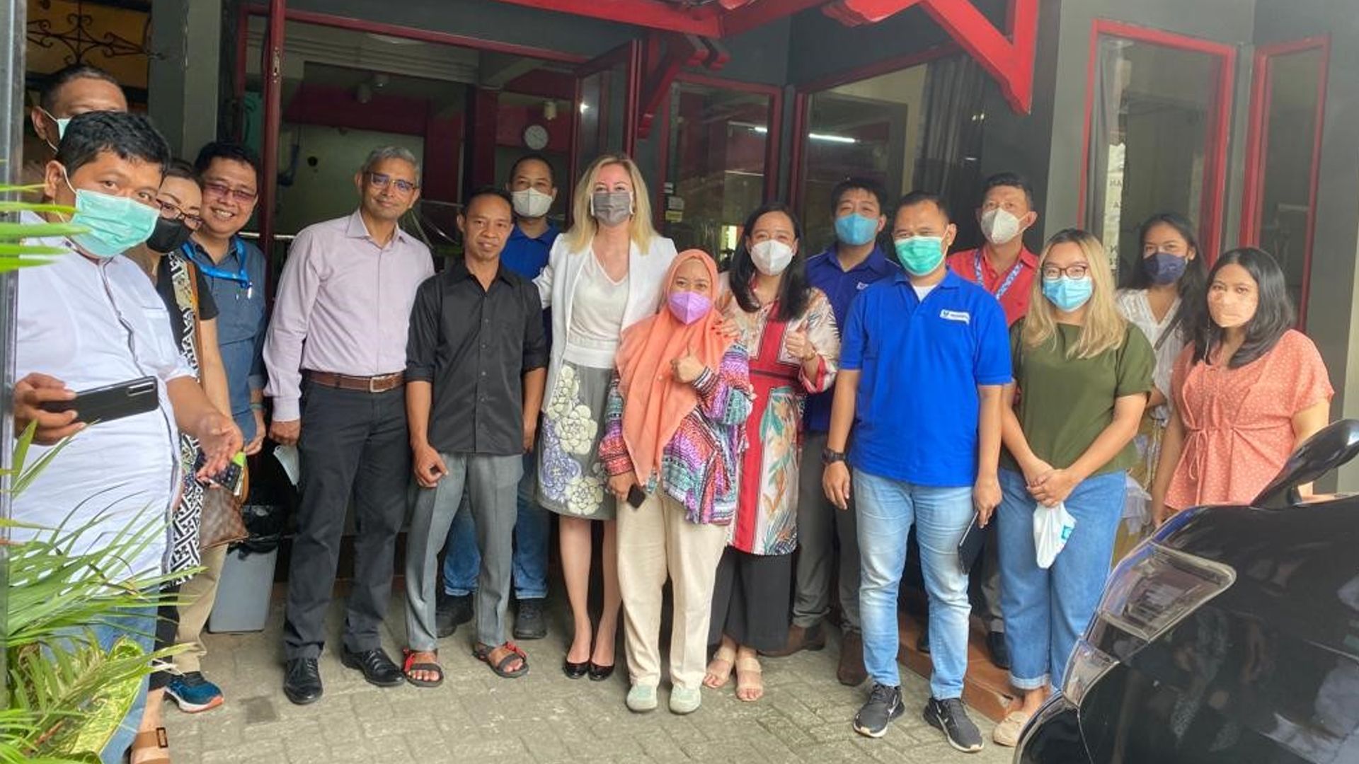 Deniz standing with a group of people on front steps of a wooden house